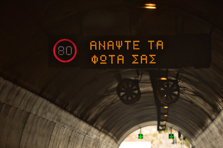 Night road tunnel with illuminated speed limit signs and directional arrows, creating a dark,...