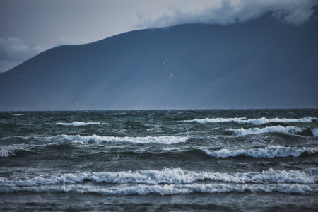 A scenic view of soft white clouds rolling over distant blue mountains under a clear sky.の写真素材