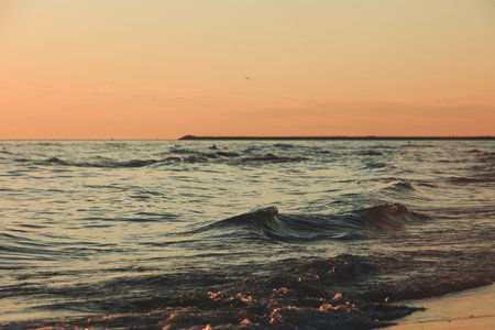 Vlora, Albania â August 2025: Vibrant sunset over the Adriatic Sea with rolling waves and distant mountain silhouettes, creating a dramatic and colorful coastal evening scene.の写真素材