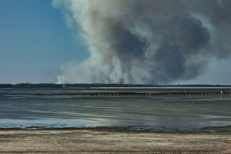 smoke from a fire in the sea on a background of blue skyの写真素材