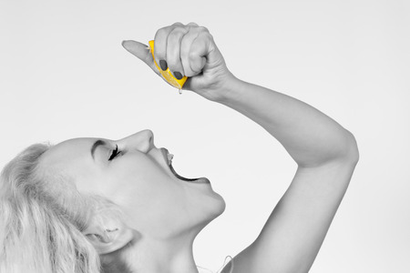 Black and White Woman Squeezes Juice from Bright Citrusの写真素材
