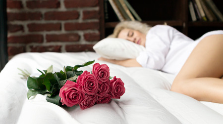 Sleeping Young Woman and Bouquet of Flowers on the Bed