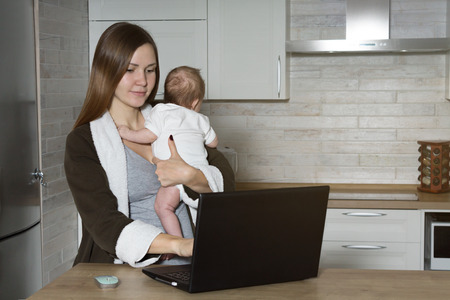 Young Mom with Baby Working at Homeの写真素材