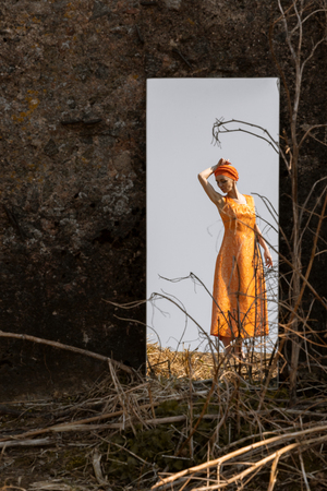 Woman in Oriental Dress In Mirror Among Dry Grass on Clear Sky Backgroundの写真素材