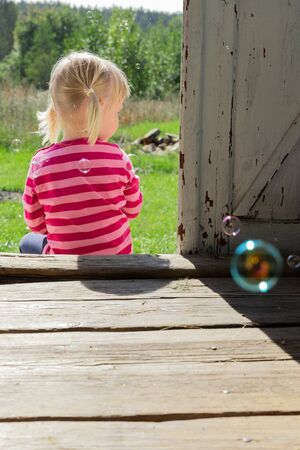 Girl Blows Bubbles in the Village. Summer Concept. Childhoodの写真素材