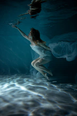 Beautiful Girl in White Dress Underwater. Water Magic. Underwater Photography. Artの写真素材