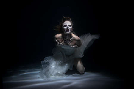 Girl Bride in Dead Man Skeleton Makeup Scares under Water. Halloween conceptの写真素材