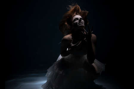 Girl Bride in Dead Man Skeleton Makeup Scares under Water. Halloween conceptの写真素材