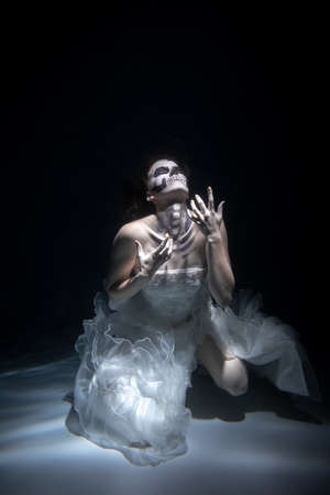 Girl Bride in Dead Man Skeleton Makeup Scares under Water. Halloween conceptの写真素材