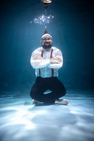 Man in White Shirt and Pants with Party Cap Underwaterの写真素材
