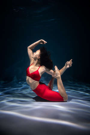 The girl is engaged in yoga under the water in sports clothes. Immersion in Meditationの写真素材