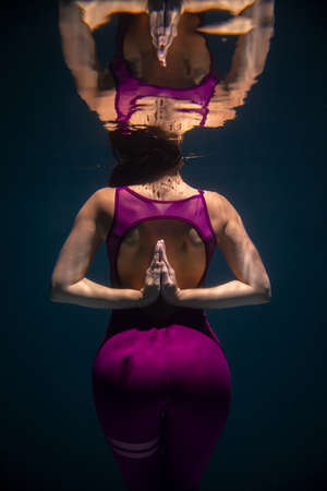 The girl is engaged in yoga under the water in sports clothes. Asanas and Meditationの写真素材