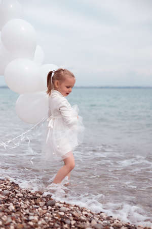 Happy Child Girl in White Dress with White Balloonsの写真素材
