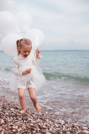 Happy Child Girl in White Dress with White Balloonsの写真素材