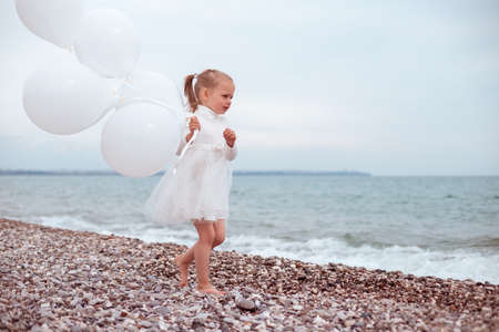 Sad Child Girl in White Dress with White Balloonsの写真素材