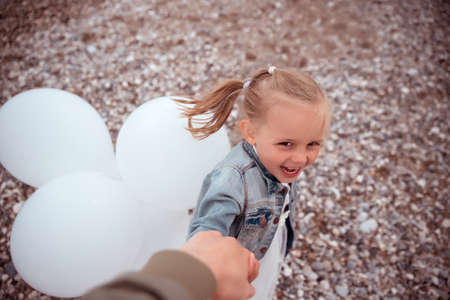Cute Little Girl in a White Dress with White Balloons