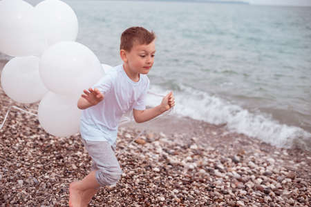 Cute Little Boy in a White Dress with White Balloonsの写真素材