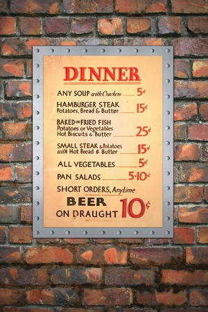 Vintage cafe menu mounted on a riveted aluminum sheet, with a brick wall background.の写真素材