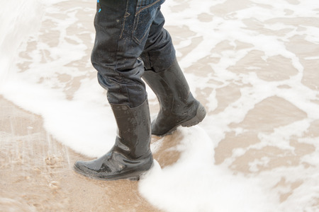child walking in the sea with bootsの写真素材