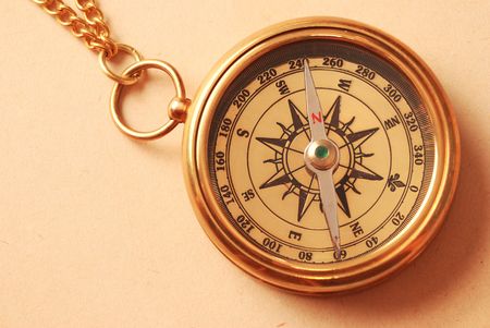 Antique brass compass over old map background  