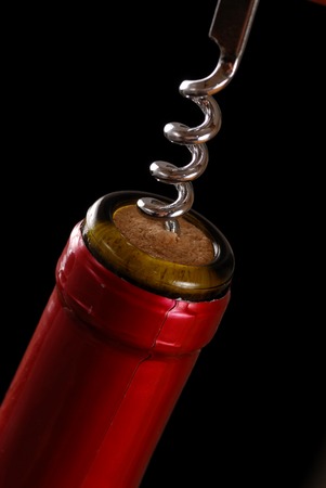 Opening a wine bottle with corkscrew, isolated on black