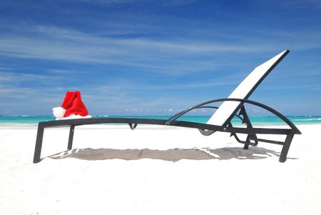 Santa's hat and chaise lounge on the beachの写真素材