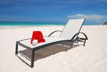 Santa's hat and chaise lounge on the beachの写真素材