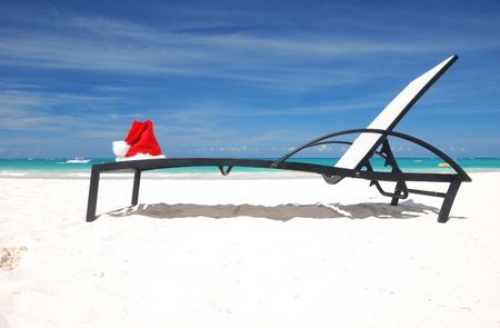 Santa's hat and chaise lounge on the beachの写真素材