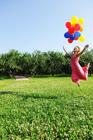 Girl jumping with balloons trying to flyの写真素材