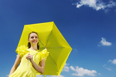Woman holding umbrella against skyの写真素材