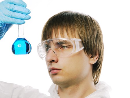 Scientist in protective wear and glasses looking at flask with reagentの写真素材