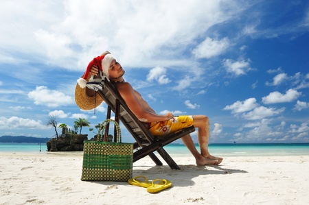 Man relaxing on the beach in santa's hatの写真素材