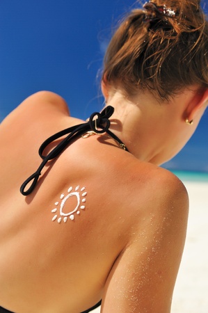 Sunscreen lotion over tan woman skin made as sun shapeの写真素材