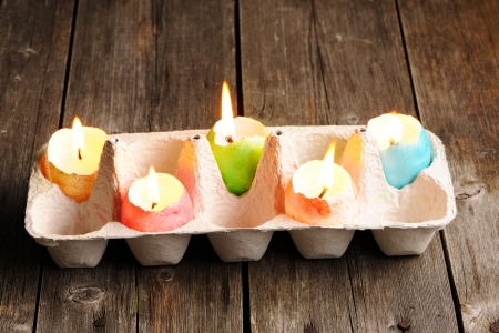 Colored easter eggs candles on wooden tableの写真素材
