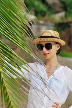 Woman in sunglasses near palm tree wearing hatの写真素材