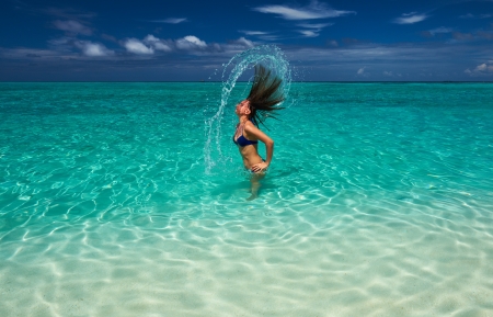 Woman splashing water with her hair in the oceanの写真素材