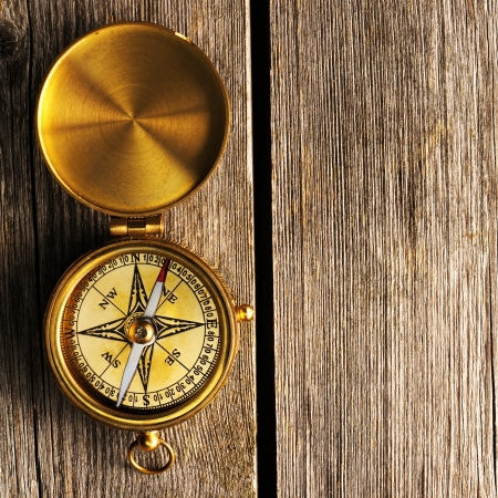 Antique brass compass over wooden backgroundの写真素材