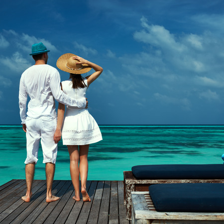Couple on a tropical beach jetty at Maldivesの写真素材