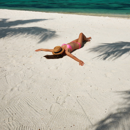Woman in bikini at tropical beach under the palm tree shadowの写真素材