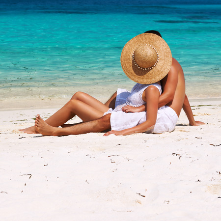 Couple in white relax on a tropical beach at Maldivesの写真素材