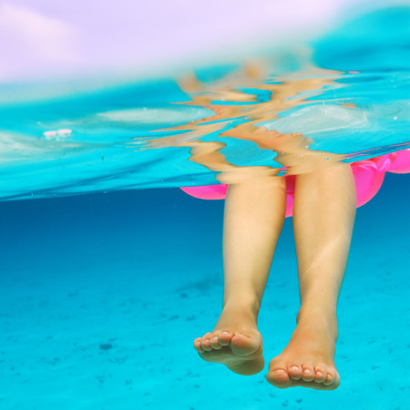 Woman relaxing on inflatable mattress at the beach, view from underwaterの写真素材