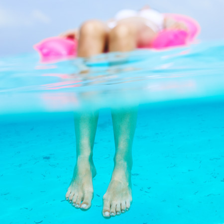 Woman relaxing on inflatable mattress at the beach, view from underwater