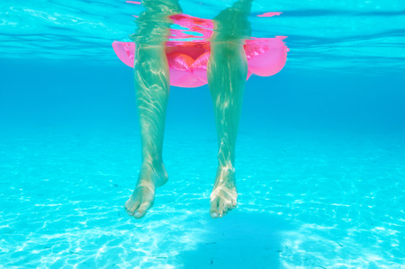 Woman relaxing on inflatable mattress at the beach, view from underwater