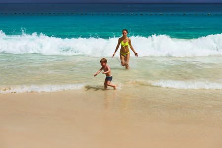 Two year old baby boy and his mother playing on beach at Seychellesの写真素材