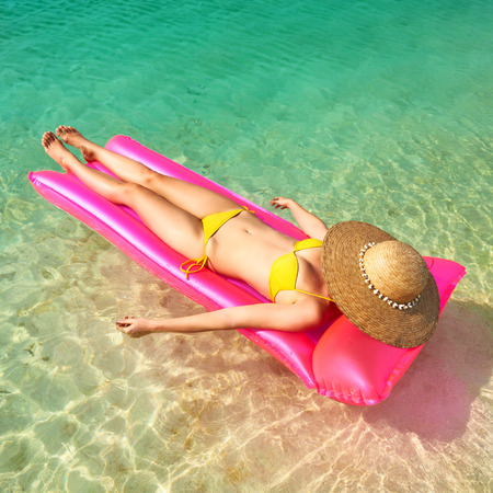 Woman relaxing on inflatable mattress at the beach