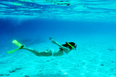 Woman with mask snorkeling in clear waterの写真素材