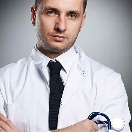 Medical doctor with stethoscope portrait against grey backgroundの写真素材