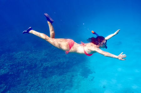 Woman with mask snorkeling in clear waterの写真素材