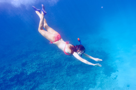 Woman with mask snorkeling in clear water
