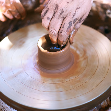 Hands working with clay on pottery wheelの写真素材